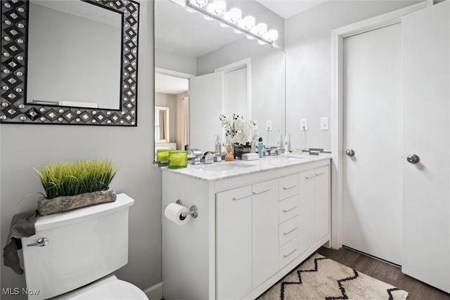 full bathroom with double vanity, toilet, a sink, and wood finished floors