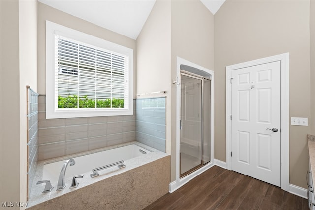 bathroom featuring a garden tub, a shower stall, wood finished floors, baseboards, and lofted ceiling