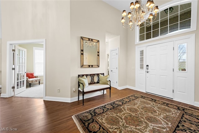 foyer featuring an inviting chandelier, baseboards, a high ceiling, and dark wood-style flooring