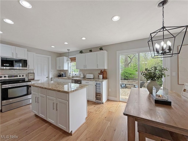 kitchen with light wood-type flooring, stainless steel appliances, recessed lighting, and white cabinetry