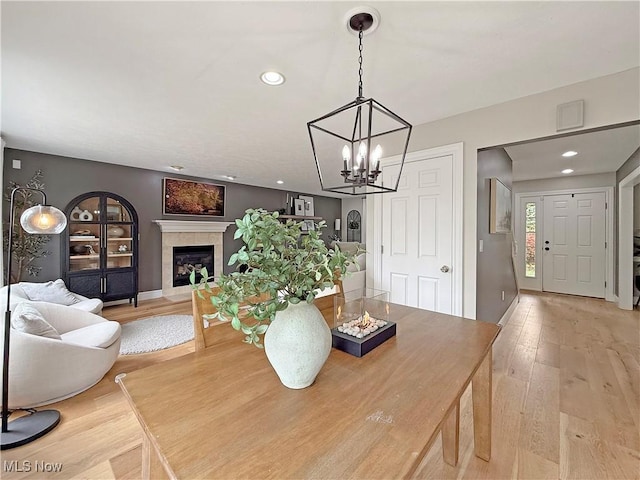 dining room featuring an inviting chandelier, baseboards, recessed lighting, a tile fireplace, and light wood-style flooring