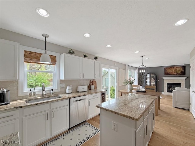 kitchen with a sink, a kitchen island, white cabinetry, and dishwasher