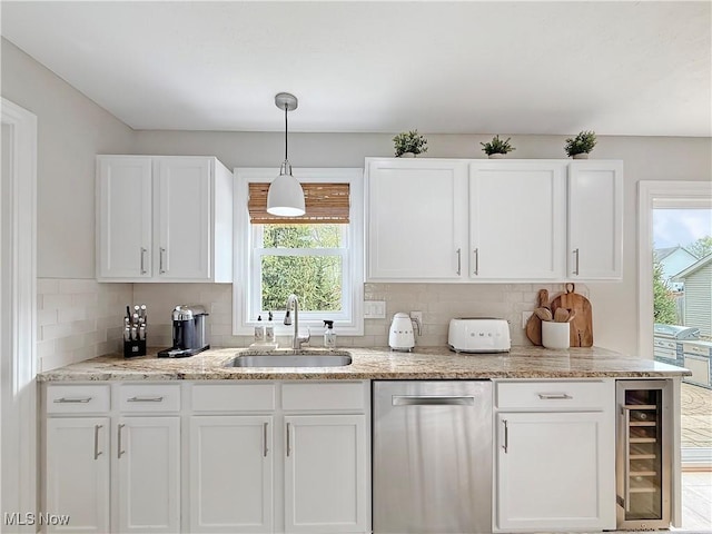 kitchen with stainless steel dishwasher, wine cooler, white cabinets, a sink, and backsplash