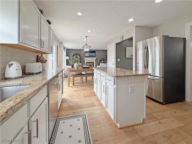 kitchen with freestanding refrigerator, recessed lighting, white cabinetry, decorative backsplash, and a kitchen island