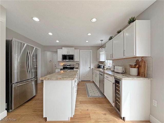 kitchen featuring a kitchen island, beverage cooler, white cabinetry, light wood finished floors, and stainless steel appliances