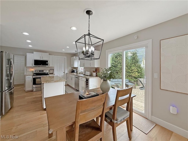 dining room with recessed lighting, light wood finished floors, and a notable chandelier