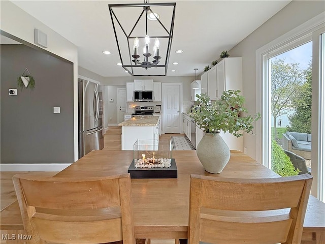 kitchen featuring a kitchen island, stainless steel appliances, a chandelier, and white cabinetry