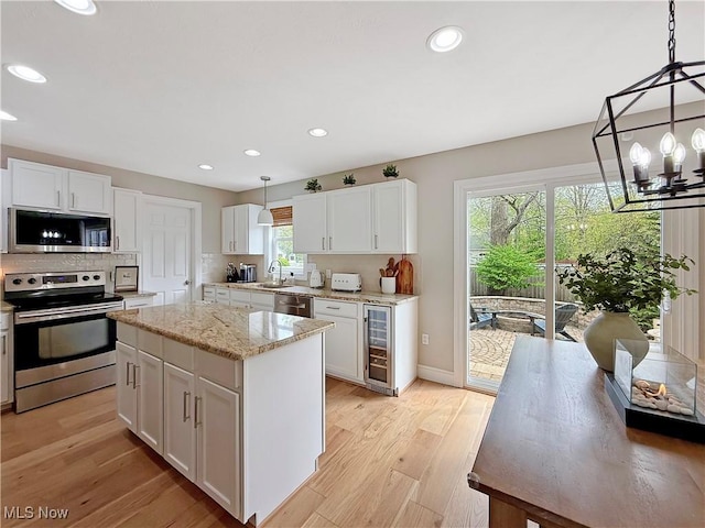kitchen featuring a sink, appliances with stainless steel finishes, beverage cooler, and white cabinetry