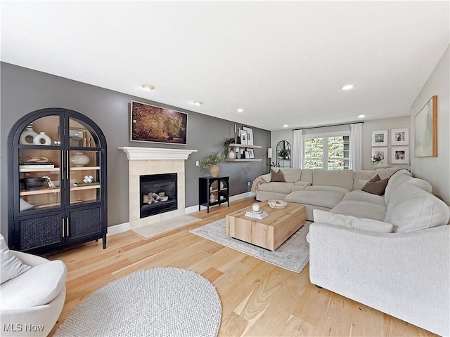 living room with recessed lighting, a tile fireplace, and light wood-style floors