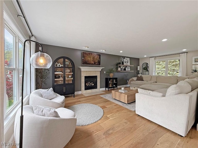 living room with recessed lighting, light wood-style flooring, and a tile fireplace