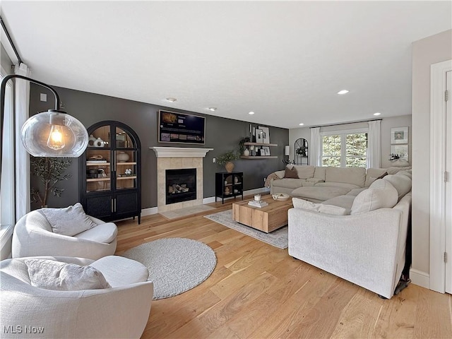 living area with a fireplace, baseboards, and light wood-type flooring