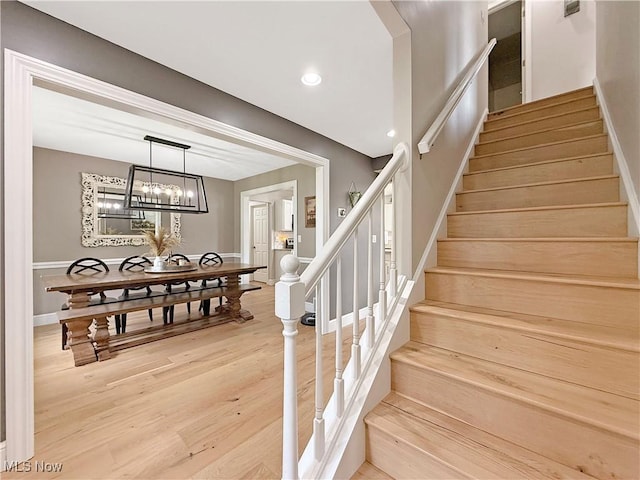 staircase featuring an inviting chandelier, baseboards, recessed lighting, and wood finished floors