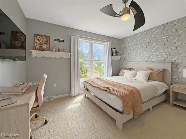bedroom featuring visible vents, baseboards, wallpapered walls, light colored carpet, and a ceiling fan