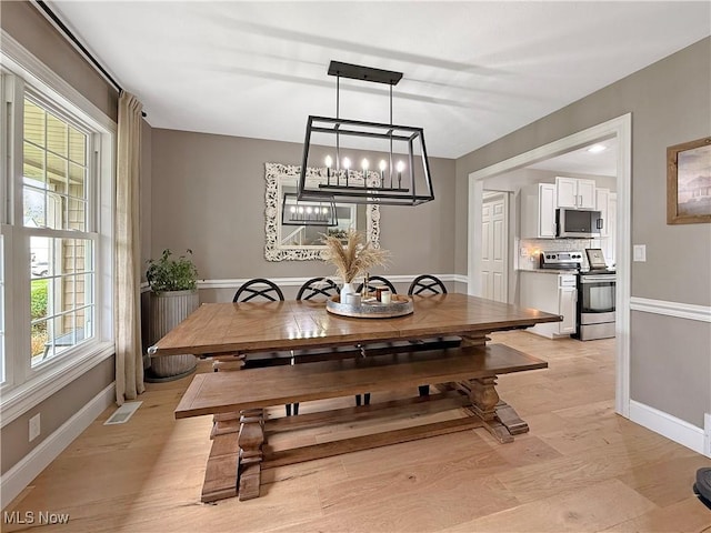 dining room featuring visible vents, light wood-style flooring, and baseboards