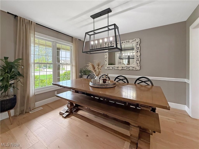dining room featuring baseboards, light wood finished floors, and a chandelier
