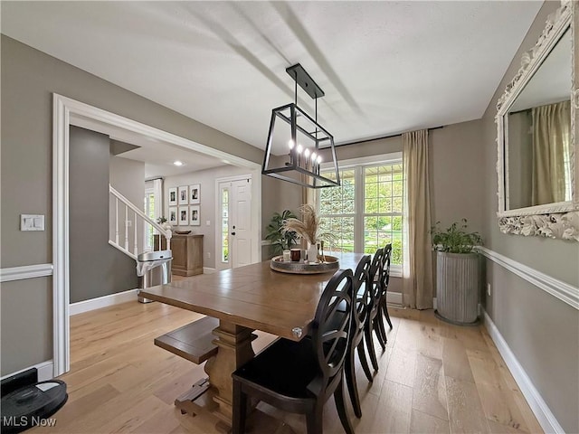 dining space with stairway, baseboards, and light wood-type flooring