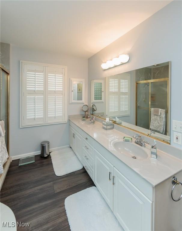 117 Royal Oak Dr, Aurora, OH 44202 - bathroom featuring double vanity, visible vents, a shower stall, wood finished floors, and a sink