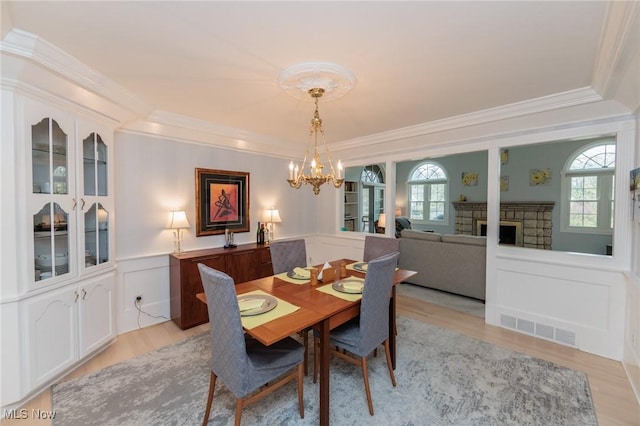 117 Royal Oak Dr, Aurora, OH 44202 - dining area featuring crown molding, a decorative wall, a chandelier, light wood-type flooring, and visible vents