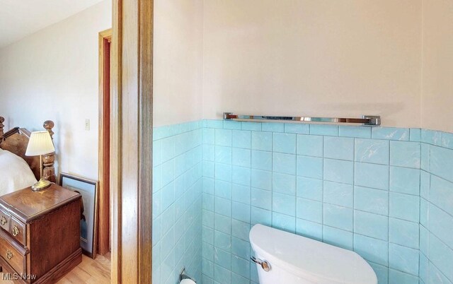half bathroom with tile walls, wainscoting, and toilet