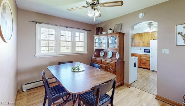 dining area featuring light wood finished floors, arched walkways, a ceiling fan, baseboards, and a baseboard heating unit
