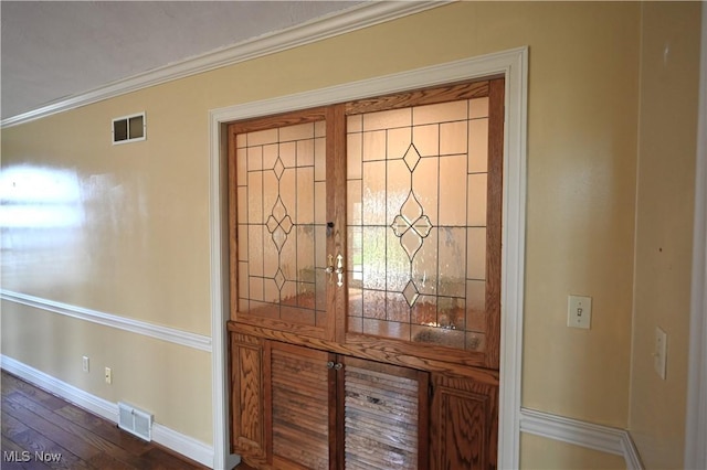 room details featuring baseboards, ornamental molding, wood finished floors, and visible vents