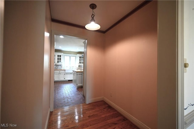 corridor featuring crown molding, baseboards, and hardwood / wood-style flooring