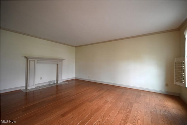 unfurnished living room with visible vents, baseboards, crown molding, and wood finished floors