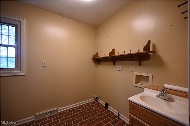 laundry area with laundry area, a sink, hookup for a washing machine, baseboards, and visible vents