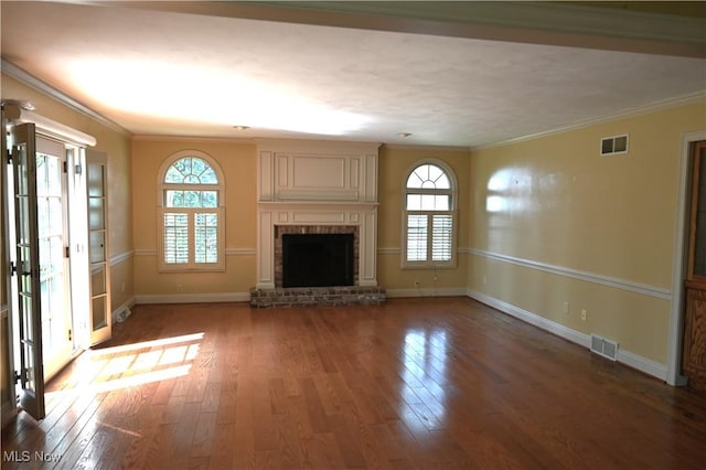 unfurnished living room with baseboards, a brick fireplace, wood finished floors, and visible vents