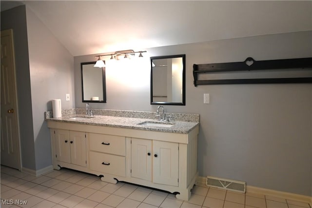 bathroom with a sink, lofted ceiling, double vanity, and visible vents