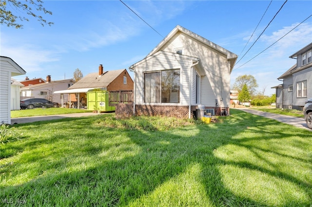 rear view of property with a lawn and central AC