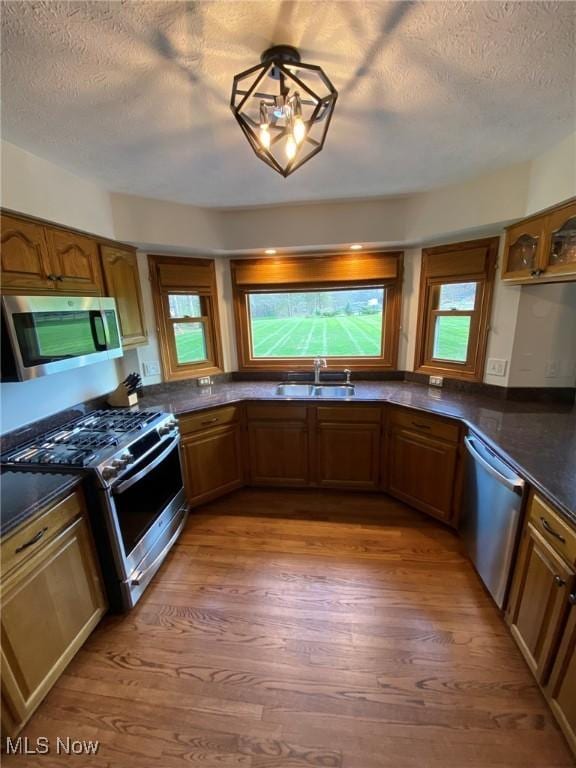 kitchen featuring a sink, dark countertops, stainless steel appliances, and brown cabinets