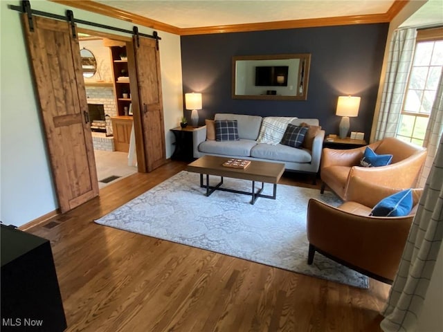 living room featuring crown molding, a barn door, baseboards, and wood finished floors