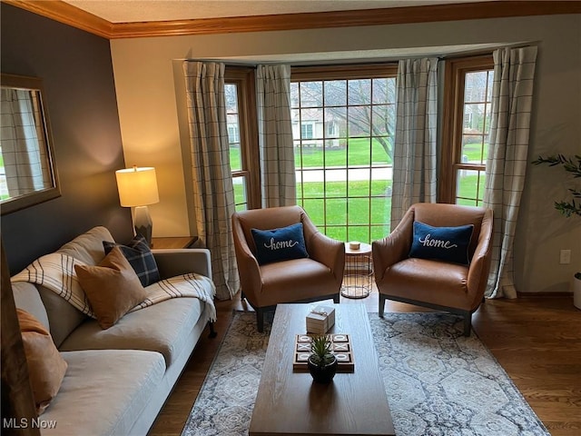 sitting room with ornamental molding and wood finished floors