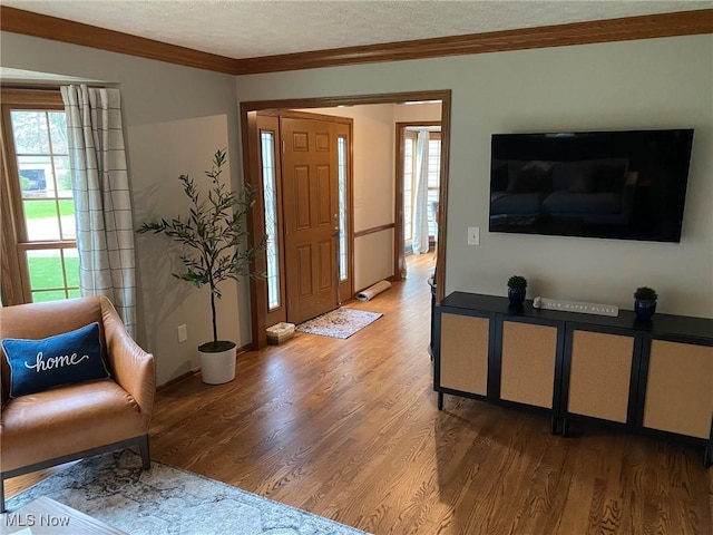 entrance foyer featuring crown molding, a textured ceiling, baseboards, and wood finished floors