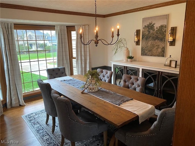 dining space featuring ornamental molding, a textured ceiling, wood finished floors, and a notable chandelier