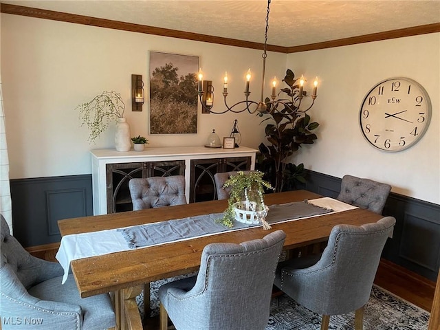 dining room featuring a decorative wall, a notable chandelier, wood finished floors, and a wainscoted wall