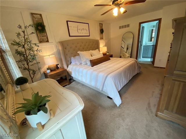 carpeted bedroom with visible vents, ceiling fan, and ensuite bath