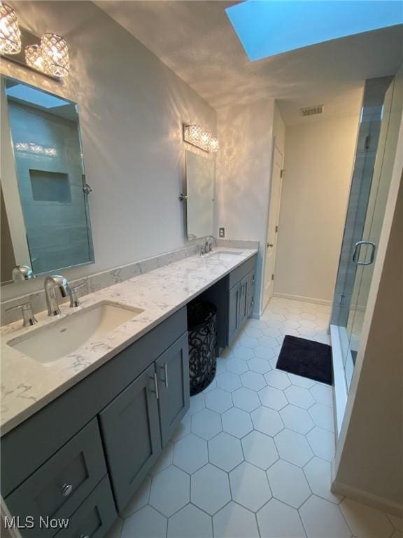 bathroom featuring a sink, a skylight, a shower stall, and visible vents