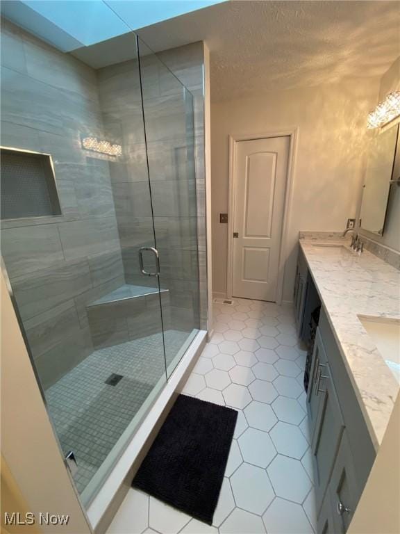 full bathroom with tile patterned flooring, a sink, double vanity, and a shower stall
