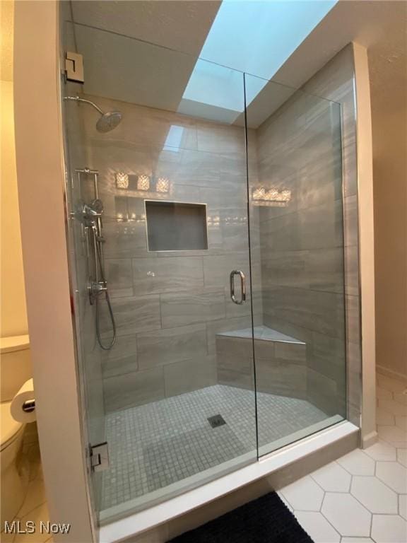 bathroom with tile patterned flooring, a stall shower, and toilet