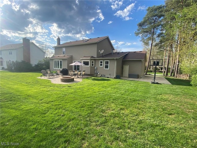 rear view of property featuring a fire pit, a patio area, and a yard