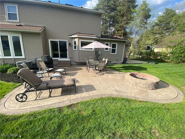 rear view of property featuring a lawn, entry steps, a fire pit, and a patio area