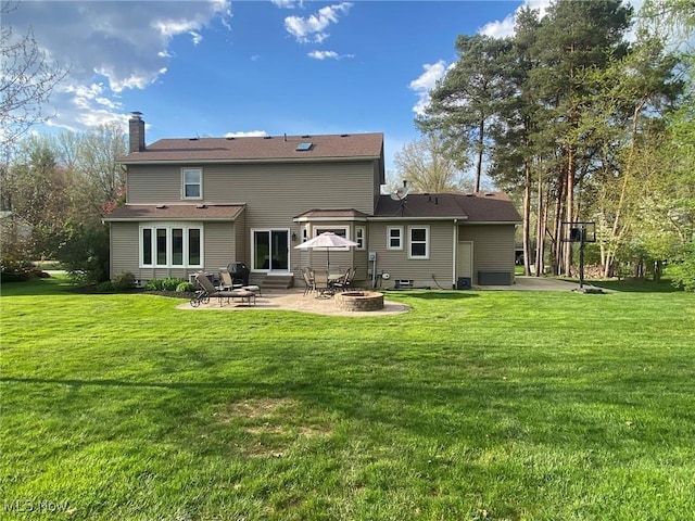 rear view of property featuring a chimney, a yard, a patio area, and an outdoor fire pit