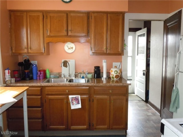 kitchen featuring brown cabinetry, a sink, wood finished floors, and light countertops