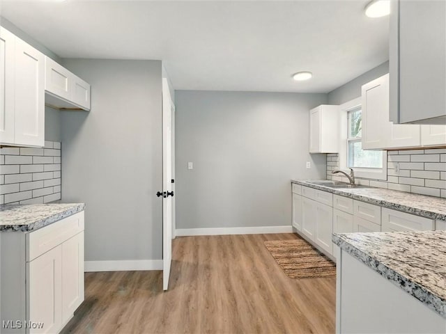 kitchen featuring light wood-style floors, a sink, and baseboards