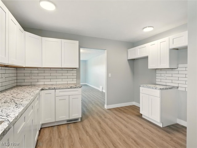 kitchen featuring white cabinets, baseboards, decorative backsplash, and light wood-style flooring