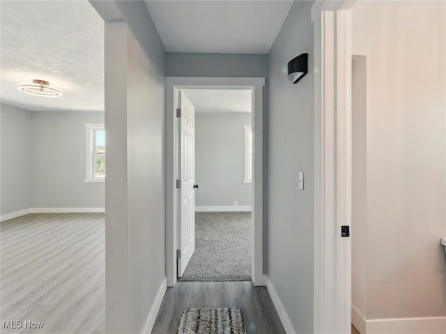 corridor with baseboards and wood finished floors