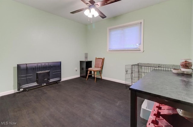 living area with baseboards, a ceiling fan, and dark wood-style flooring