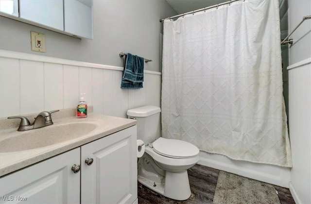 full bathroom featuring wainscoting, vanity, toilet, shower / bathtub combination with curtain, and wood finished floors